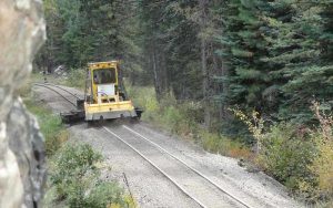 KNG 800 on dirt railway tracks with green trees on side.