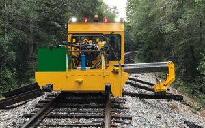 The KTR 450 remove railway ties from a front perspective with trees on both sides of unit.