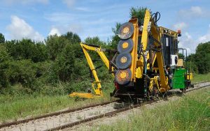 Brushcutter attachment option mounted onto the side of railway machinery.