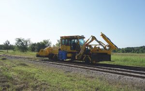 The Brushcutter option on unit on railway tracks in the middle of a field.