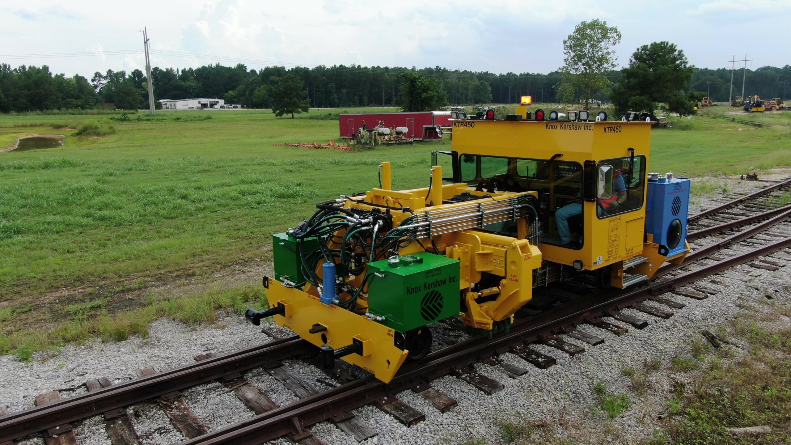 KTR 450 side view on railway track with power lines and green trees behind.
